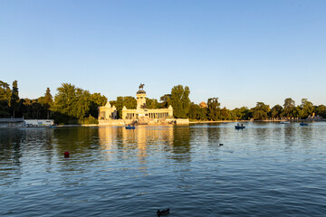 Obraz premium Retiro Park, Madrid, Spain. Crystal Palace, lake with swans, glass structure, architecture. Lake and temple on the horizon, fountains and decorated with colorful plants and flowers, family leisure.