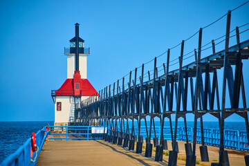 Lighthouse on Pier with Red Roof and Blue Rails during Golden Hour