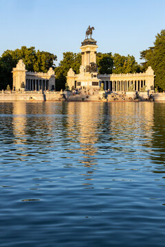 Retiro Park, Madrid, Spain. Crystal Palace, lake with swans, glass structure, architecture. Lake and temple on the horizon, fountains and decorated with colorful plants and flowers, family leisure.