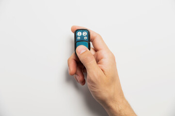 Remote control for door or garage or gate in male hand on white background. Modern technologies and...