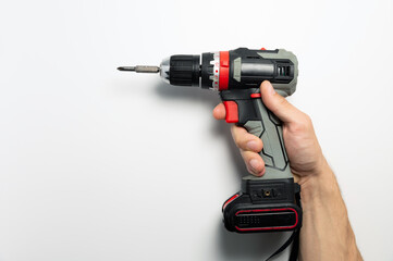 Cordless screwdriver in male hand on white background. Close-up of working tool, household help at hand