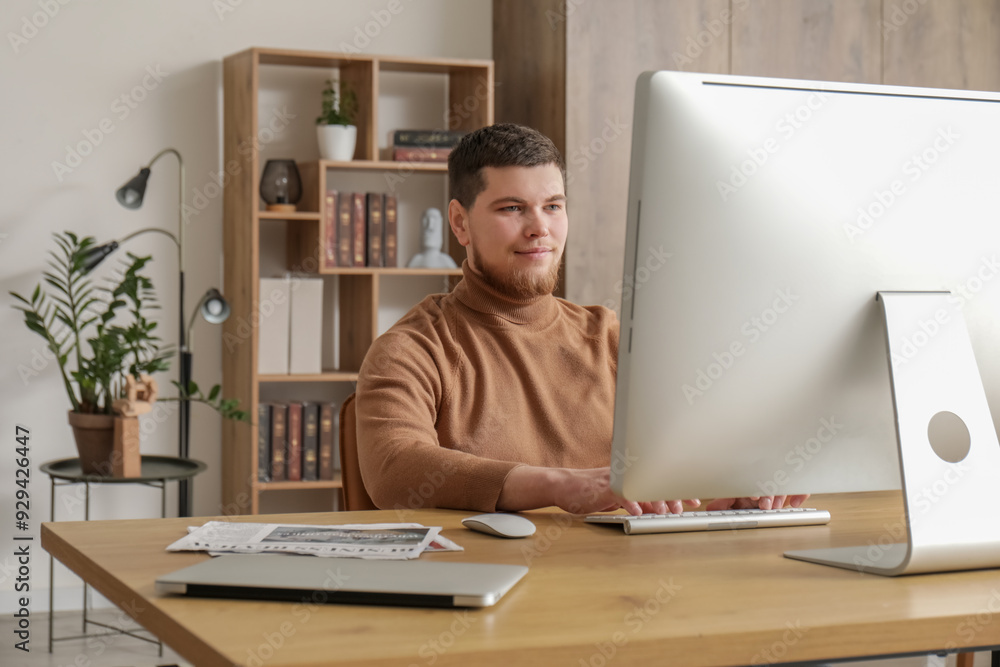 Poster young bearded man using computer at table in office