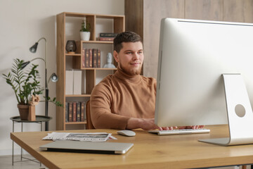Young bearded man using computer at table in office