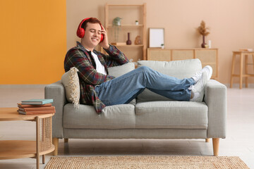 Obraz premium Young man listening to audiobook and resting on sofa in living room