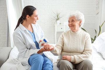 Obraz premium Physical therapist measuring senior woman's temperature in bedroom
