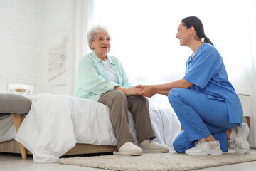 Fototapeta premium Physical therapist with senior woman holding hands in bedroom