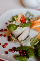 Herring fillet with herbs and pomegranate on white plate