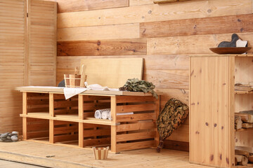 Wooden bench with towels and whisk in sauna