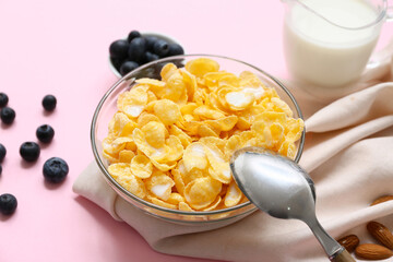 Napkin, berries, bowl with cornflakes and milk on pink background, closeup