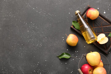 Composition with fruits, wooden tray and bottle of fresh apple cider on black background