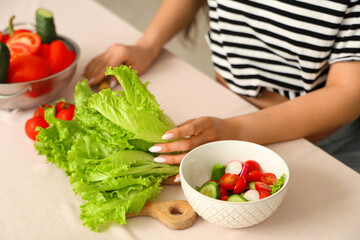 Young pregnant woman preparing fresh vegetable salad at home, closeup