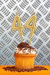 Chocolate cupcake with candle number 44 - Birthday on industrial metallic background.