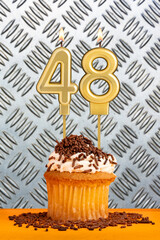 Chocolate cupcake with candle number 48 - Birthday on industrial metallic background.