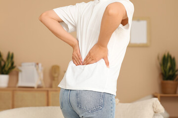 Young woman suffering from back pain at home