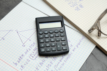 Copybooks with math formulas and calculator on table, closeup