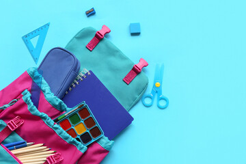 Modern school backpack with different stationery supplies on blue background