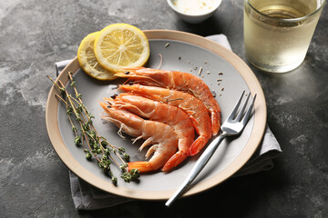 Plate with tasty boiled shrimps and lemon on dark background