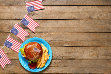 Tasty burger with french fries and flags of USA on wooden background. American Independence Day celebration