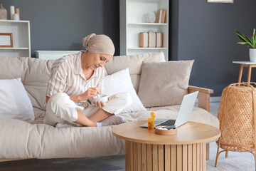 Mature woman after chemotherapy grinding weed on sofa at home
