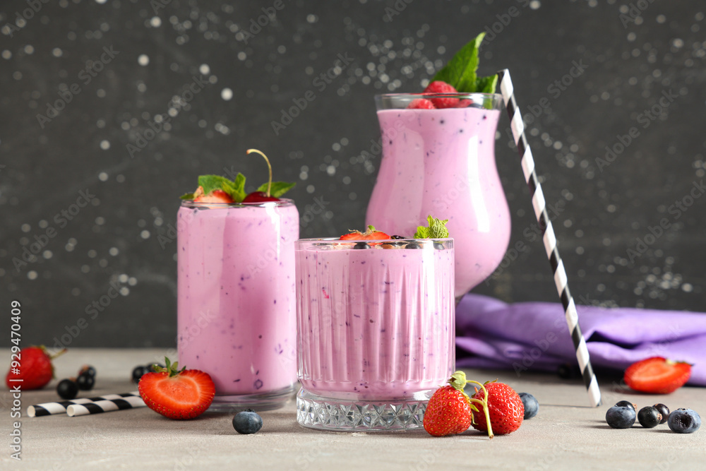 Wall mural glasses of fresh smoothie with different berries and mint on grey table