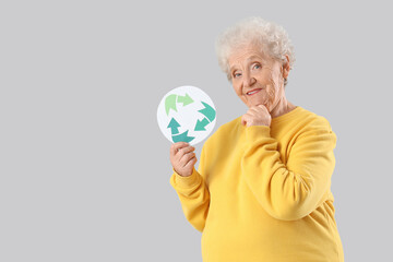 Senior woman with recycle sign on light background. Waste sorting concept