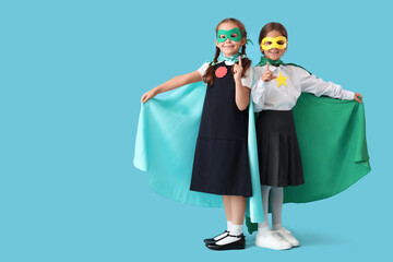Schoolgirls dressed as superheroes showing gun gesture on blue background