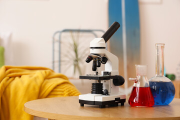 Microscope with chemical flasks on table in teenager's room, closeup