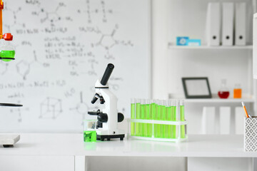 Modern microscope with test tubes on table in laboratory