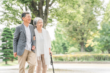 Fototapeta premium 公園を話しながら歩く日本人の高齢者夫婦（シニア・男女） 