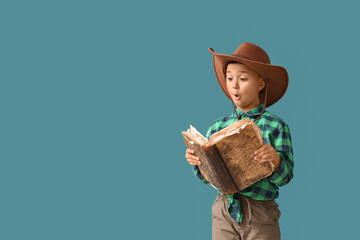Surprised little cowboy reading book on blue background