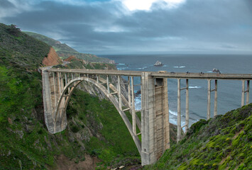 Four motorcycles cross Bixby Bridge with cloudy sky