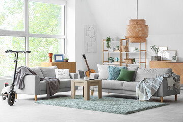 Interior of living room with electric scooter, sofas and table