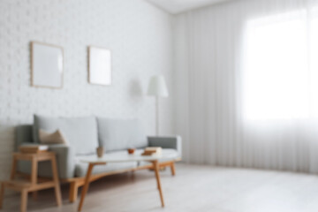 Blurred view of living room with grey sofa, table and frames