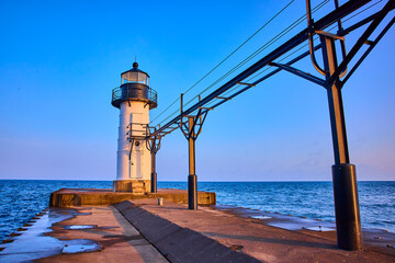 White Lighthouse on Pier at Golden Hour with Industrial Walkway Perspective