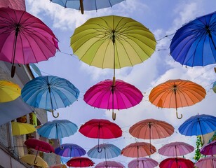 Colorful umbrellas suspended overhead, creating a vibrant, cheerful street scene.