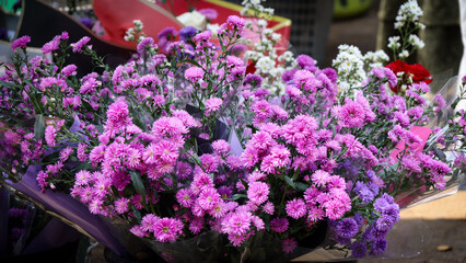 A close-up of a vibrant bouquet featuring purple and pink flowers wrapped in decorative paper. Perfect for celebrating special occasions. Suitable for 