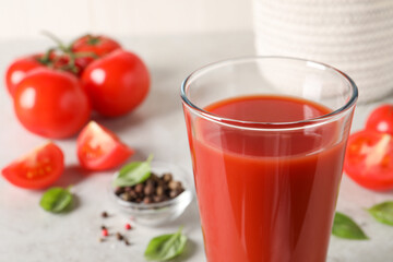 Tasty tomato juice in glass, basil leaves and fresh vegetables on table, closeup