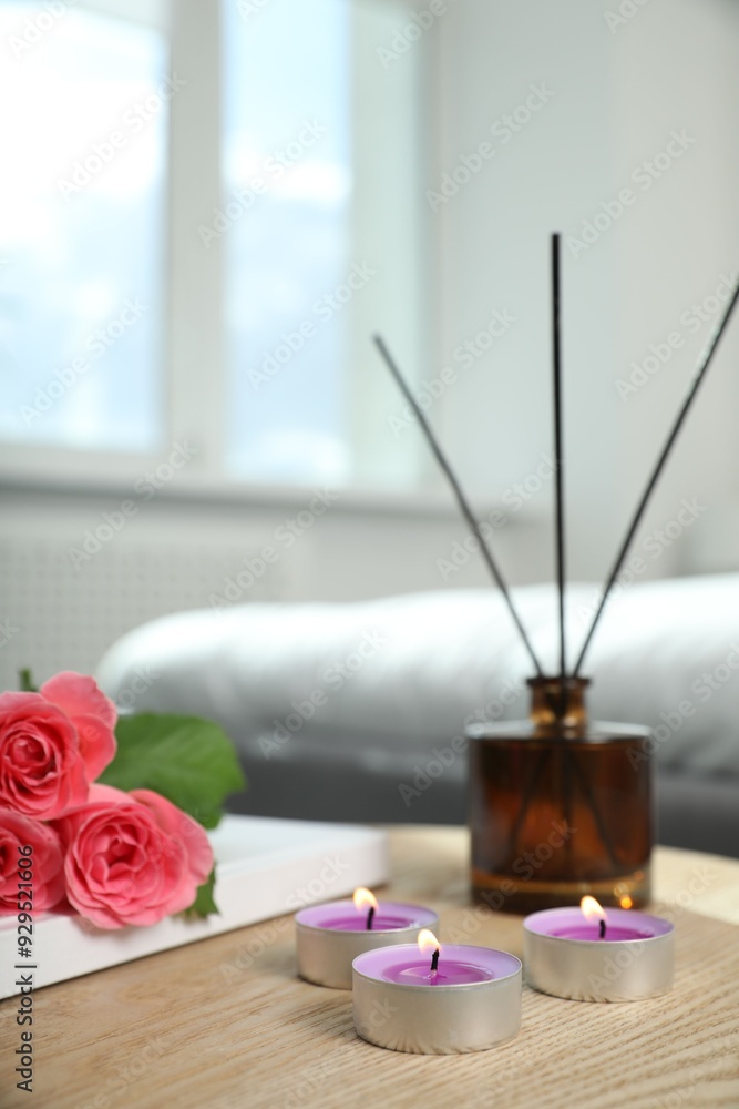 Canvas Prints Burning candles, rose flowers, book and reed diffuser on wooden table indoors