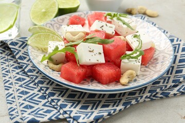 Delicious watermelon salad with feta cheese, cashew nuts and spices on light table