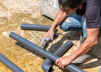 Worker use electronic grinding disk blade cutting grey pipe.