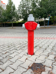 Red fire hydrant on a housing estate. A newly installed hydrant on a block-paved sidewalk in an urban neighborhood. Background.