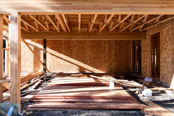 Summer construction season, two story new house build in progress at the framing stage, messy job site with building materials out front
