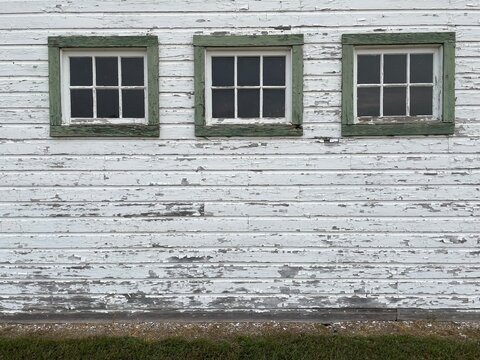 Tres ventanas de madera antiguas sobre pared deteriorada en color blanco. 