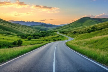 Naklejka premium Serene winding road through lush green hills under a colorful sunset sky, perfect for nature and travel photography.