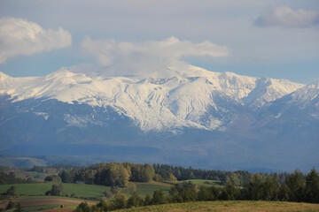 秋の丘陵畑作地帯と冠雪の山並み