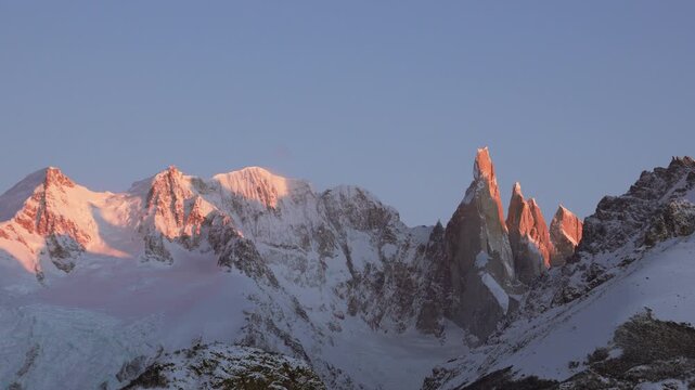 Red sunrise light illuminates Cerro Torre and Cordon Adela walls in Southern Patagonia near El Chalten. Static zoomed-in view