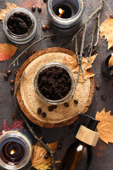 Coffee scrub for the body, in a transparent jar with autumn leaves, on a dark background.