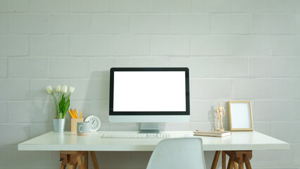 Front view of blank computer monitor on white table in home office, for graphic display montage.