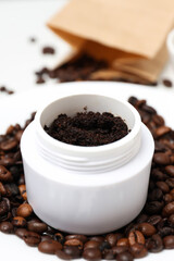 Coffee body scrub, in a container with whole coffee beans, on a white background.