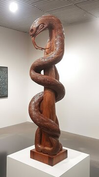 Maori carving, of a Taniwha (mythical creature), displayed in a cultural center, under bright natural light